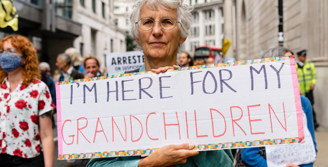Senior women holding a sign during protest saying "I'm here for my Grandchildren".